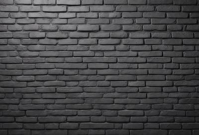 The primary subject of the image is a brick wall. The setting is a dark room, and the visual style is a black and white photo. The dominant colors are black and white, creating a moody atmosphere.