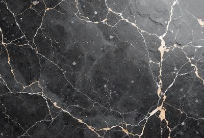 The primary subject of the image is a black marble countertop with a gold-colored pattern. The setting is a kitchen, and the visual style is a close-up of the marble countertop. The dominant colors are black and gold, creating a luxurious and elegant atmosphere.