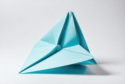 The primary subject of the image is a blue paper airplane. The setting is a white background, and the visual style is a photo. The colors and mood of the image are predominantly blue, giving it a calm and serene atmosphere.