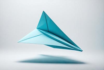 The primary subject of the image is a blue paper airplane. The setting is a white background, which provides a clean and minimalist appearance. The visual style is a photo, capturing the paper airplane in its natural form. The colors and mood of the image are predominantly blue, giving it a calm and serene atmosphere.