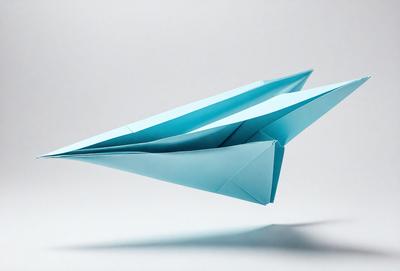 The primary subject of the image is a blue paper airplane. The setting is a white background, and the visual style is a photo. The colors and mood of the image are predominantly blue, creating a calm and serene atmosphere.