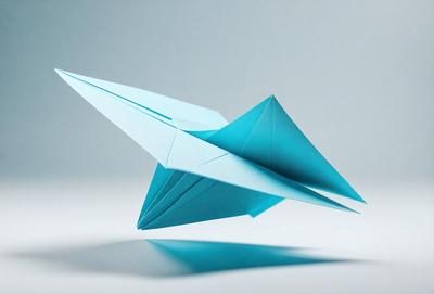 The primary subject of the image is a blue paper airplane. The setting is a white background, which provides a clean and uncluttered environment for the airplane. The visual style is a close-up of the paper airplane, showcasing its details and structure. The colors and mood of the image are predominantly blue, giving it a calm and serene atmosphere.