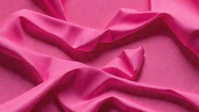 The primary subject of the image is a pink fabric, which is the main object, scene, or focus of the image. The setting or background is a pink surface, which adds to the overall atmosphere. The visual style of the image is a close-up of the pink fabric, showcasing its texture and details. The colors and mood of the image are predominantly pink, creating a warm and inviting atmosphere.