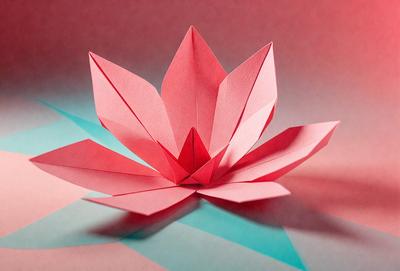 The primary subject of the image is a paper flower, which is the main object, scene, or focus of the image. The setting is a table, and the visual style is a photo. The dominant colors in the image are pink and red, creating a warm and vibrant atmosphere.