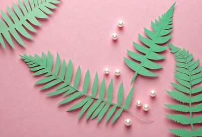 The primary subject of the image is a green leaf with pearls attached to it. The leaf is placed on a pink background, which adds a contrasting color to the scene. The visual style of the image is a combination of a photo and a drawing, creating a unique and artistic representation of the leaf with pearls. The colors and mood of the image are predominantly pink and green, giving it a warm and inviting atmosphere.