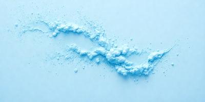 The primary subject of the image is a blue substance, possibly a powder or a liquid, that is spreading out and forming a line. The setting is a white surface, which provides a clean and uncluttered backdrop for the blue substance. The visual style of the image is a close-up, focusing on the details of the blue substance. The colors and mood of the image are predominantly blue, creating a sense of calmness and tranquility.