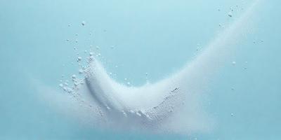The primary subject of the image is a close-up of a white substance, possibly a powder or a foam, with a blue background. The visual style appears to be a photo, and the colors and mood suggest a clean and fresh atmosphere.