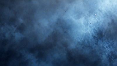 The primary subject of the image is a cloudy sky. The setting is a dark, cloudy day with a blue hue. The visual style is a photo of the sky, showcasing the clouds and their dark, moody atmosphere. The colors and mood of the image are predominantly dark and gloomy, with the blue hue adding a touch of calmness to the scene.