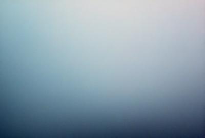 The primary subject of the image is a large, empty, and foggy sky. The setting is a vast, open space with no visible landmarks or objects. The visual style is a natural, outdoor scene with a sense of vastness and tranquility. The colors and mood are predominantly grays and blues, creating a calm and serene atmosphere.