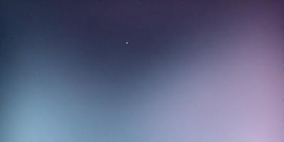 The primary subject of the image is a star, which is located in the middle of the night sky. The setting is a dark, cloudless night with a clear view of the star. The visual style of the image is a photo, capturing the beauty of the night sky. The colors and mood of the image are predominantly dark, with the star being the only bright and prominent feature in the scene.