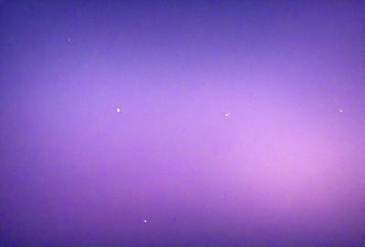 The image features a purple sky with a few stars scattered throughout the scene. The primary subject is the night sky, which is the main focus of the image. The setting is a dark, star-filled sky, and the visual style is a natural, outdoor environment. The colors and mood of the image are predominantly purple, creating a serene and peaceful atmosphere.