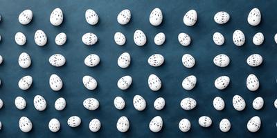The primary subject of the image is a collection of white eggs. The setting is a blue surface, which serves as the background. The visual style is a close-up of the eggs, showcasing their details. The dominant colors are white and blue, creating a clean and serene atmosphere.