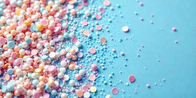 The primary subject of the image is a close-up of a blue surface covered with a variety of colorful, round, and bumpy objects. The setting appears to be a table or a similar surface. The visual style of the image is a combination of photo and digital art, as it captures the vibrant colors and textures of the objects. The colors and mood of the image are lively and cheerful, with the blue surface providing a contrasting backdrop for the colorful objects.