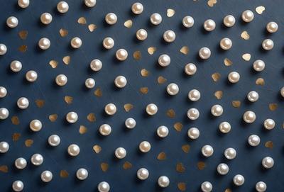 The primary subject of the image is a large number of white pearls, which are arranged in a pattern on a blue surface. The setting appears to be a wall or a table, and the visual style is a close-up of the pearls. The colors in the image are predominantly white and blue, creating a clean and elegant atmosphere.