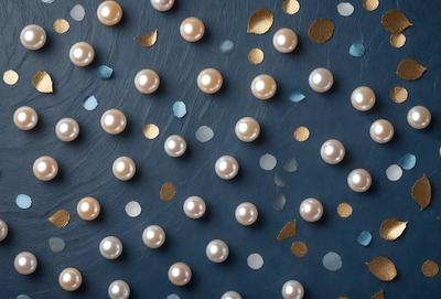 The primary subject of the image is a close-up of a blue background with a large number of pearls scattered across it. The pearls are of various sizes and are arranged in a visually appealing manner. The setting appears to be a dark room, possibly a studio or a room with a blue-toned wall. The visual style of the image is a combination of a photo and digital art, creating a unique and artistic representation of the pearls. The colors and mood of the image are predominantly