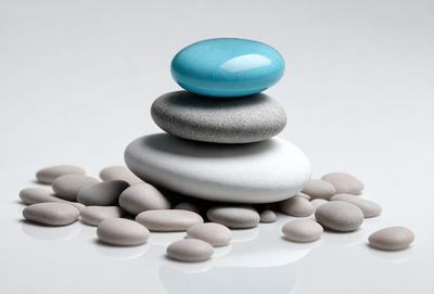 The primary subject of the image is a stack of four white and blue rocks. The setting is a white surface, which provides a clean and minimalist backdrop for the rocks. The visual style is a close-up of the rocks, showcasing their unique colors and textures. The overall atmosphere is calm and serene, as the rocks are neatly arranged and seem to be a part of a larger, unseen structure.