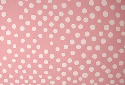 The primary subject of the image is a pattern of polka dots on a pink background. The setting is a wall, and the visual style appears to be a combination of a photo and a digital art or illustration. The dominant colors are pink and white, creating a warm and cheerful atmosphere.