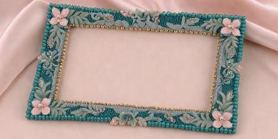 The primary subject of the image is a decorative frame with a pink background. The frame is adorned with a blue border and features a design of flowers. The setting is a pink surface, which complements the frame's color scheme. The visual style of the image is a combination of digital art and illustration, creating a unique and eye-catching design. The colors and mood of the image are predominantly pink and soft, giving it a warm and inviting atmosphere.