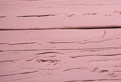 The primary subject of the image is a wooden surface with a pinkish hue. The setting is a room with a wooden floor, and the visual style appears to be a photo. The colors and mood of the image are predominantly pink, giving it a warm and inviting atmosphere.