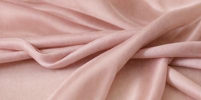 The primary subject of the image is a piece of pink fabric. The setting is a table, and the visual style is a close-up of the fabric. The colors and mood of the image are predominantly pink, creating a soft and delicate atmosphere.