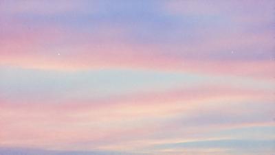 The primary subject of the image is a beautiful, colorful sky with a pink and purple hue. The sky is filled with swirling clouds, creating a mesmerizing and serene atmosphere. The setting is outdoors, with the sky serving as the backdrop for the scene. The visual style of the image is a combination of photo and digital art, as it captures the vibrant colors and swirling clouds in a captivating manner. The colors and mood of the image are predominantly
