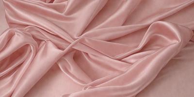 The primary subject of the image is a piece of pink fabric. The setting is a close-up view of the fabric, showcasing its texture and color. The visual style is a realistic representation of the fabric, and the colors and mood are predominantly pink, giving the image a soft and delicate appearance.