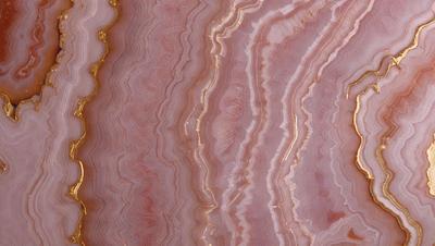 The primary subject of the image is a close-up of a marbled stone wall. The setting is a natural environment, with the wall being the main focus of the scene. The visual style is a photo, capturing the intricate patterns and textures of the marbled stone. The dominant colors in the image are pink and gold, creating a warm and natural atmosphere.