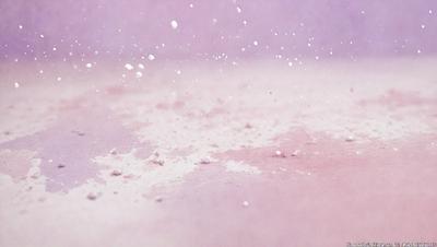 The primary subject of the image is a close-up of a white powder, possibly flour or sugar, on a pink surface. The setting appears to be a kitchen or a dining area, as the white powder is sprinkled on a dining table. The visual style of the image is a close-up, which emphasizes the texture and details of the white powder. The colors in the image are predominantly pink and white, creating a warm and inviting atmosphere.