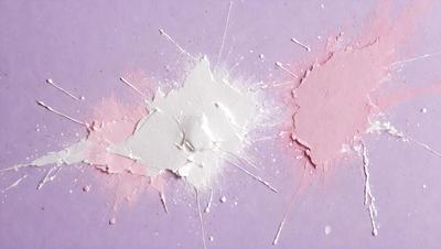 The primary subject of the image is a white substance, possibly a cream or a paint, that is spreading or dripping onto a purple surface. The setting appears to be a table or a countertop, with the white substance creating a visually striking contrast against the purple background. The visual style of the image could be interpreted as a photo, digital art, or an illustration, as the white substance appears to be dripping or spreading in a controlled manner. The colors and mood of the image are