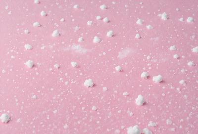 The primary subject of the image is a pink surface with white snowflakes scattered across it. The setting appears to be a pink background, and the visual style is a close-up of the pink surface with the white snowflakes. The colors and mood of the image are predominantly pink and white, creating a warm and inviting atmosphere.