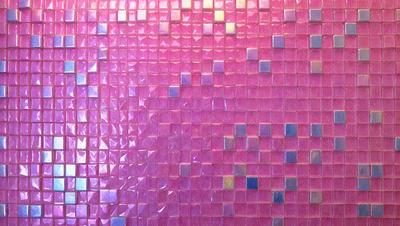 The primary subject of the image is a pink and purple tile wall. The setting is a room with a pink and purple tile wall, which serves as the background. The visual style is a close-up of the tile wall, showcasing the intricate pattern and colors. The dominant colors are pink and purple, creating a warm and inviting atmosphere.