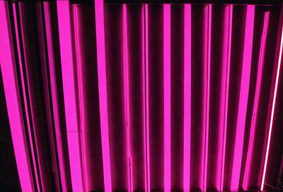 The primary subject of the image is a pink lighted wall. The setting is a room with a pink lighted wall, which creates a unique and visually striking atmosphere. The visual style of the image is a close-up of the pink lighted wall, emphasizing its color and texture. The dominant colors in the image are pink and purple, giving the scene a warm and inviting mood.