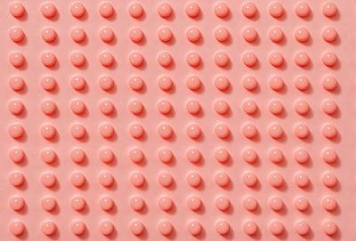 The primary subject of the image is a large pink surface with numerous small, round, pink objects on it. The objects are arranged in a pattern, creating a visually appealing and cohesive design. The setting appears to be a room with a pink background, which adds to the overall atmosphere of the scene. The visual style of the image is a combination of photo and digital art, as it captures the intricate details of the pink objects and their arrangement on the pink surface. The colors and mood of