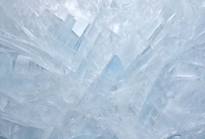 The primary subject of the image is a large, intricate, and colorful crystal formation. The setting is a white background, which provides a clean and minimalistic appearance. The visual style is a combination of photo and digital art, creating a unique and eye-catching image. The dominant colors are blue and white, giving the scene a cool and calming atmosphere.