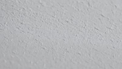 The primary subject of the image is a white wall with a textured surface. The setting is a room with a white background. The visual style is a close-up of the wall, showcasing its texture. The colors and mood of the image are predominantly white, giving it a clean and minimalist appearance.