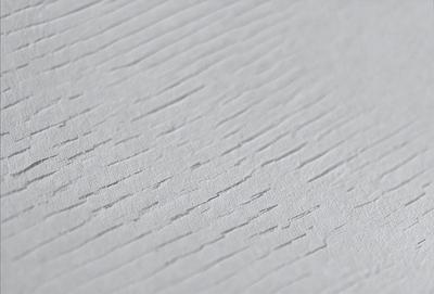 The primary subject of the image is a white surface with a pattern of lines and grooves. The setting is a white wall, and the visual style appears to be a close-up of the wall. The colors and mood of the image are predominantly white, giving it a clean and minimalist appearance.