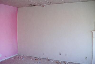 The primary subject of the image is a white wall in a room. The setting is a room with a pink wall, and the visual style is a photo. The colors and mood of the image are predominantly white and neutral, creating a clean and minimalist atmosphere.