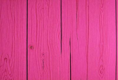 The primary subject of the image is a wooden surface, possibly a wall or a table, with a pink color. The setting appears to be indoors, and the visual style is a close-up of the wooden surface. The dominant colors in the image are pink and brown, creating a warm and inviting atmosphere.