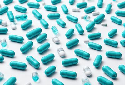 The primary subject of the image is a large number of blue and white pills arranged in a pattern. The setting is a white background, and the visual style appears to be a digital art or illustration. The dominant colors are blue and white, creating a clean and professional appearance. The overall atmosphere of the image is organized and visually appealing.