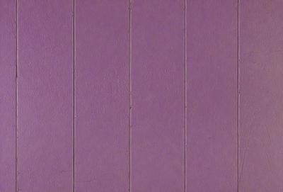 The primary subject of the image is a purple wall with a wooden texture. The setting is a room with a purple wall, and the visual style is a close-up of the wall. The dominant colors are purple and brown, creating a calm and soothing atmosphere.