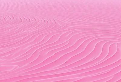 The image features a pink surface with a pattern of waves. The primary subject is the pink surface, which appears to be a sandy or textured surface. The setting is a beach or a similar environment, as the waves are a common element in such locations. The visual style is a close-up of the pink surface, showcasing the intricate pattern of the waves. The colors and mood of the image are predominantly pink, creating a warm and inviting atmosphere.