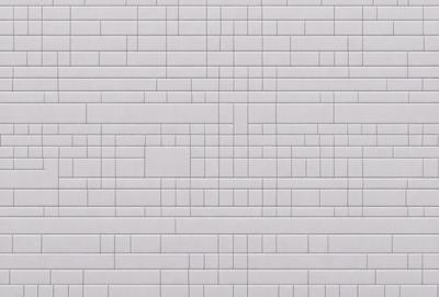 The primary subject of the image is a large brick wall. The setting is a grey brick wall, which serves as the background. The visual style is a photo, capturing the brick wall in detail. The colors and mood of the image are predominantly grey, giving it a neutral and somewhat industrial appearance.