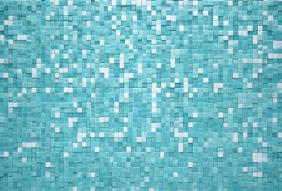 The primary subject of the image is a blue tile wall with a pattern of white squares. The setting is a room with a blue tile floor. The visual style is a close-up of the blue tile wall, showcasing the intricate pattern of white squares. The colors and mood of the image are predominantly blue and white, creating a calm and serene atmosphere.