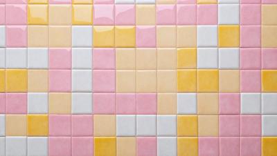 The primary subject of the image is a pink and yellow tile wall. The setting is a room with a pink and yellow tile wall, which serves as the background. The visual style is a close-up of the tiles, showcasing the pattern and texture of the wall. The dominant colors are pink and yellow, creating a warm and inviting atmosphere.