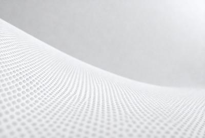 The primary subject of the image is a white surface with a pattern of small holes. The setting is a white wall, and the visual style appears to be a photo. The dominant colors are white and grey, creating a clean and minimalist atmosphere.