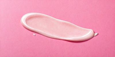 The primary subject of the image is a pink lipstick, which is the main focus of the image. The lipstick is placed on a pink surface, creating a visually appealing contrast between the lipstick and the background. The visual style of the image is a close-up of the lipstick, showcasing its texture and color. The colors and mood of the image are predominantly pink, giving it a warm and inviting atmosphere.