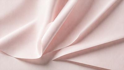 The primary subject of the image is a piece of pink fabric. The setting is a pink background, which creates a visually appealing contrast with the fabric. The visual style of the image is a close-up of the fabric, showcasing its texture and details. The colors and mood of the image are predominantly pink, giving it a soft and delicate appearance.