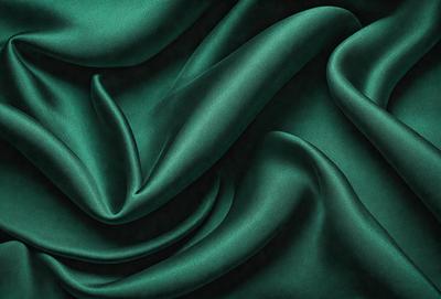 The primary subject of the image is a close-up of a green fabric, possibly a piece of cloth or a curtain. The setting is a dark background, which contrasts with the green fabric. The visual style appears to be a photo, as the fabric is captured in detail. The colors and mood of the image are predominantly green, creating a calm and soothing atmosphere.