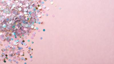 The primary subject of the image is a pink background with a sprinkle of glittery, colorful confetti. The setting is a pink wall, and the visual style is a close-up of the confetti on the wall. The colors and mood of the image are predominantly pink, with the confetti adding a touch of color and sparkle to the scene.