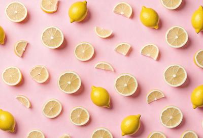 The primary subject of the image is a pattern of lemon slices, which are arranged in various shapes and sizes. The setting is a pink background, which adds a vibrant and warm tone to the scene. The visual style is a combination of photo and digital art, creating a realistic yet artistic representation of the lemon slices. The colors and mood of the image are predominantly yellow and fresh, reflecting the natural and inviting nature of the lemon slices.